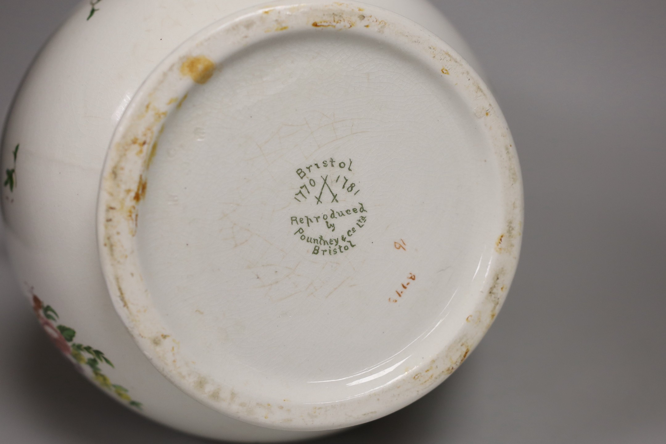 A Pountney jug, commemorating 100 years of the Bristol porcelain factory 1770 -1781, decorated with floral sprays and sprigs, green line border, 27cm high, printed mark. 26.5cm